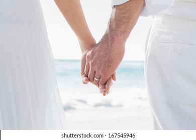 Bride and groom holding hands close up at the beach