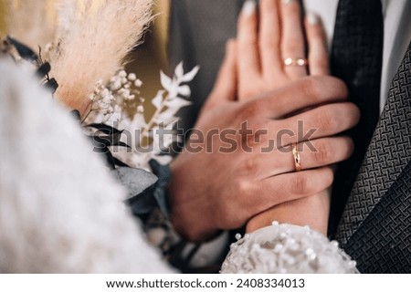 Bride and groom holding hands, close up.