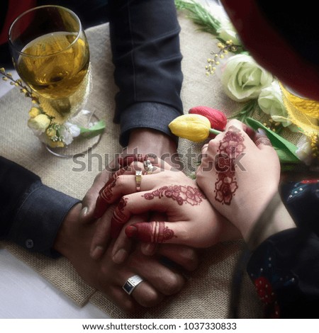 Bride and groom holding hands decorated with henna. shallow dept of field.