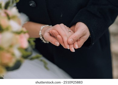 A bride and groom are holding hands in front of a bouquet of flowers. The bride is wearing a white dress and the groom is wearing a black suit. Scene is romantic and happy