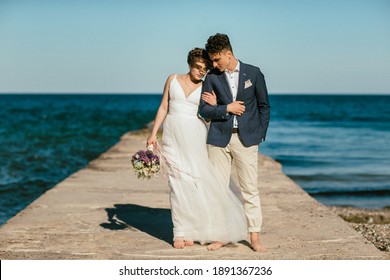 bride and groom holding hands walk on the pier. wedding photoset. sea wedding. newlyweds pose by the seashore. honeymoon by the sea