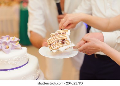 Bride And Groom Holding Slice Of Wedding Cake