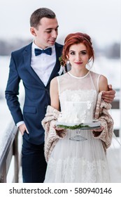 Bride And Groom Holding Winter Wedding Cake 