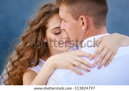 bride and groom hugging at the background of water