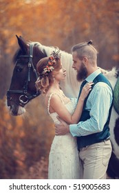 Bride and groom hugging in a forest near the horse in the autumn forest, wedding walk