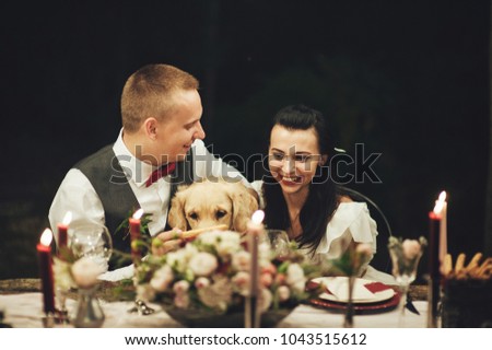 Bride and groom hugging Labrador dog at wedding celebration