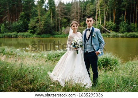 Bride and groom hugging near lake in nature. Wedding photoshoot. Place for text.