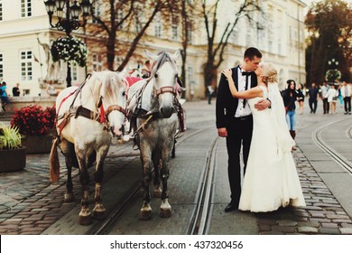 Bride and groom kiss behind horses somewhere in the old part of the city