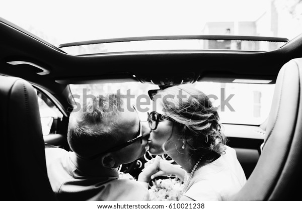 Bride and\
groom kiss each other sitting on front\
seat