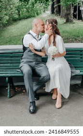 the bride and groom kiss while sitting on a bench