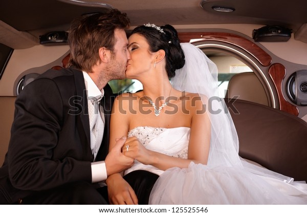 Bride and\
groom kissing in limousine on\
wedding-day.