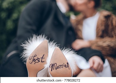 The Bride And Groom Are Kissing And The Text On The Bride's Shoes Is Just Married. Wedding Concept 