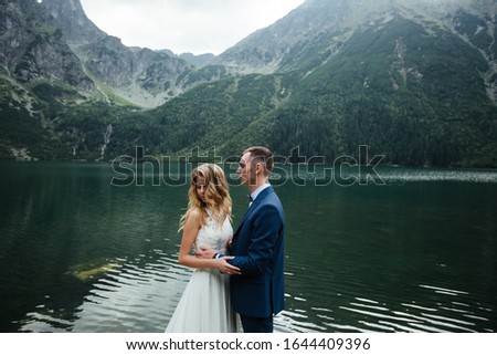 The bride and groom near the lake in the mountains. A couple together against the backdrop of a mountain landscape. Morskie Oko Lake. Tatra mountains in Poland