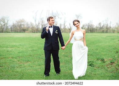 Bride And Groom On A Rainy Wedding Day Walking Under An Umbrella