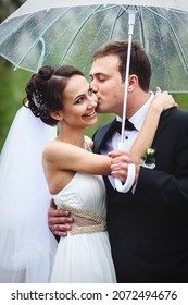 Bride And Groom On A Rainy Wedding Day Walking Under An Umbrella