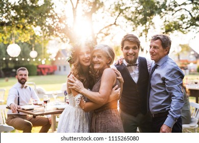 Bride, groom with parents posing for the photo at wedding reception outside in the backyard. - Powered by Shutterstock