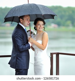 Bride And Groom Portrait On Their Wedding Day By The Rain