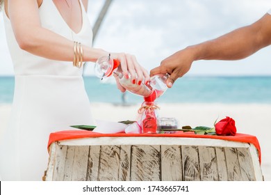 Bride And Groom Pouring Colorful Different Colored Sands Into The Crystal Vase Close Up During Symbolic Nautical Decor Destination Wedding Marriage Unity Ceremony On Sandy Beach In Front Of The Ocean 