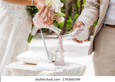 Bride And Groom Pouring Colorful Different Colored Sands Into The Crystal Vase Close Up During Symbolic Nautical Decor Destination Wedding Marriage Unity Ceremony On Sandy Beach In Front Of The Ocean 