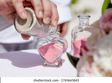 Bride And Groom Pouring Colorful Different Colored Sands Into The Crystal Vase Close Up During Symbolic Nautical Decor Destination Wedding Marriage Unity Ceremony On Sandy Beach In Front Of The Ocean 