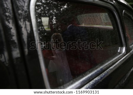 Similar – Eine Frau in einer mit großem Ausschnitt sitzt in ihrem Auto auf der rechten Seite vorne und schminkt sich, legt Schmuck an. Man kann sie durch die Reflexion in der Windschutzscheibe nicht erkennen