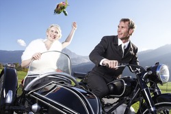Bride And Groom Riding Motorcycle With Sidecar In Rural Area