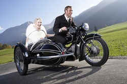 Bride And Groom Riding Motorcycle With Sidecar In Rural Area