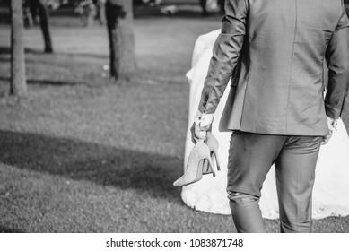 Bride And Groom Running On Green Grass Of Golf Course, Back View. Happy Wedding Couple Walking In The Forest. Black And White Photo