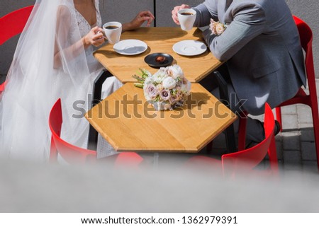 the bride and groom sit at a table in a cafe drinking coffee
