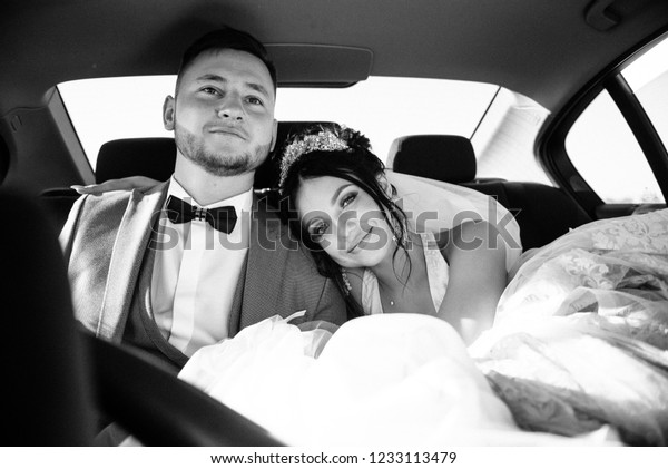 The
bride and groom are sitting in the back seat of a
car
