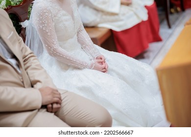 Bride And Groom Sitting In A Church During A Catholic Wedding Ceremony.