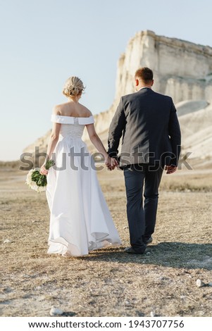 Bride and groom standing against big white rock