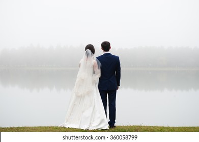 bride and groom standing in front of the lake and looking into the distance in the direction of the park  Valentine's Day - Powered by Shutterstock