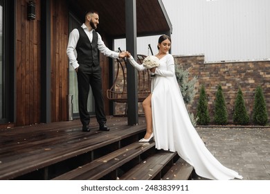 A bride and groom are standing on a wooden staircase, with the bride holding a bouquet. Scene is romantic and happy, as the couple is getting ready for their wedding - Powered by Shutterstock