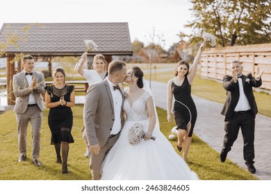 A bride and groom are surrounded by their wedding party, all dressed in black and white. The bride is wearing a white dress and the groom is wearing a suit. The wedding party is all smiling - Powered by Shutterstock