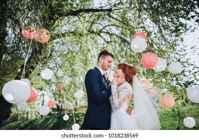 The Bride And Groom Tenderly Embrace In The Summer Park. The Red-haired Bride. Loving Wedding Couple Outdoor. Bride And Groom.