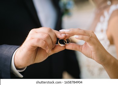 bride and groom together hold their golden wedding rings