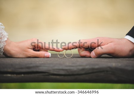 bride and groom touching rings by finger