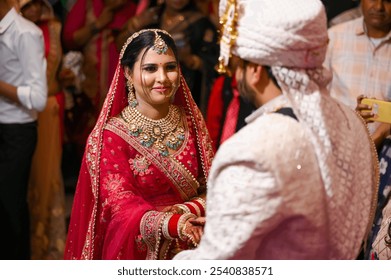 A bride and groom in traditional Indian wedding attire during their wedding ceremony, surrounded by guests. - Powered by Shutterstock