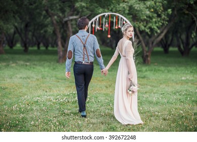 Bride And Groom Walking Away In Spring Park Outdoors