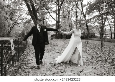A bride and groom are walking down a path in the woods. The bride is wearing a white dress and the groom is wearing a suit. They are holding hands and smiling