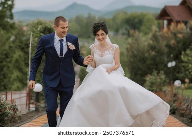 A bride and groom are walking down a path in a garden. The bride is wearing a white dress and the groom is wearing a blue suit