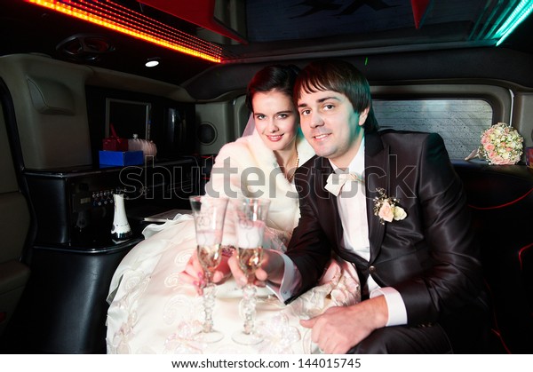 Bride and
groom in wedding limousine with
champagne
