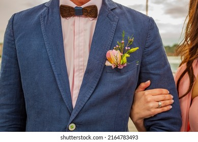 Bride And Groom. Wedding Ring And Wedding Bouquet. Spring Summer Celebration. He Puts A Ring On Her Hand. Blue Wedding Suit. Purple Bouquet And Gold Rings.