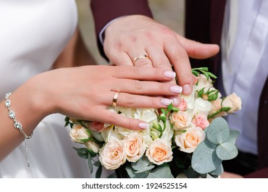 The bride and groom in wedding suits are holding together a wedding bouquet of white and lilac roses. Men's blue classic suit for men and girls white dress. Newlyweds without faces