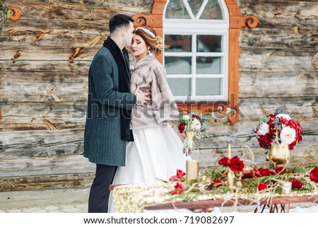 The bride and groom in the winter against the background of the old house. 