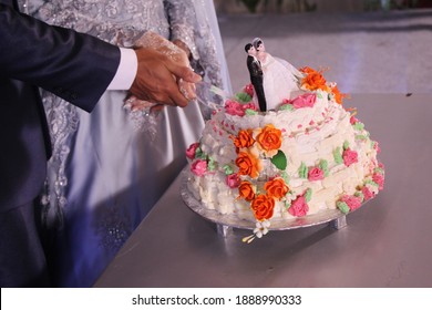 
The Bride And Groom's Second Hand Cut The Cake On The Table. Indonesian Wedding Reception