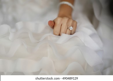 Bride hand with beautiful diamond ring on white dress