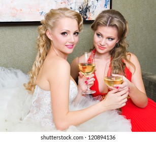 The bride and her bridesmaid with a glass of wine on the sofa