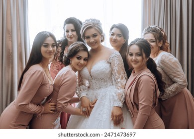 A bride and her bridesmaids pose for a picture. The bride is wearing a white dress and the bridesmaids are wearing pink dresses. Scene is happy and celebratory, as the bride - Powered by Shutterstock